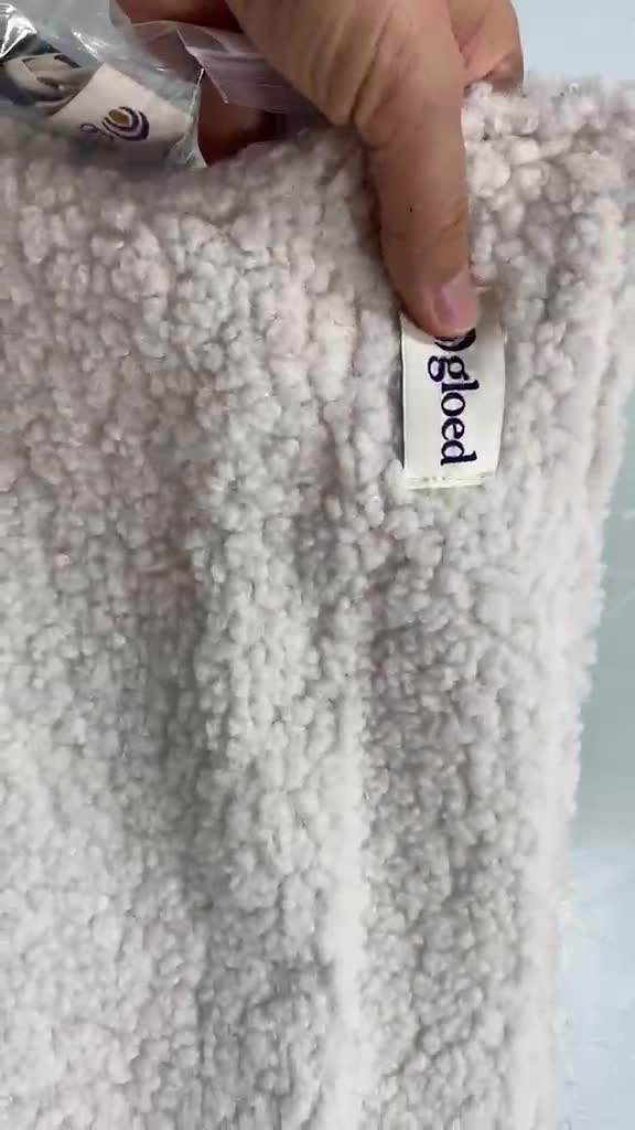 GLOED heated cushion with its woven brand label, shown in supplier footage
